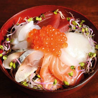 Big bowl of sushi rice with assorted sashimi such as tuna, salmon, horse mackerel, scallop, squid, salmon roe and radish sprout